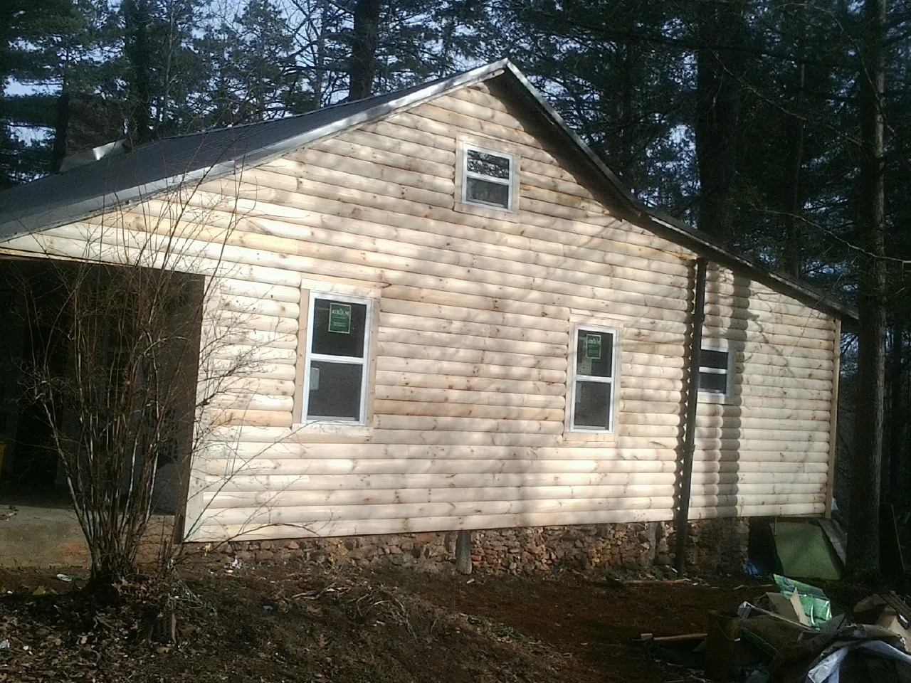 New log siding and dark metal roofing on a gable end in Brandeis