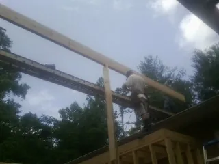 Carpenter setting a ridge beam over a new addition frame — Ice Dam Removal by Roofing Brothers in Brandeis