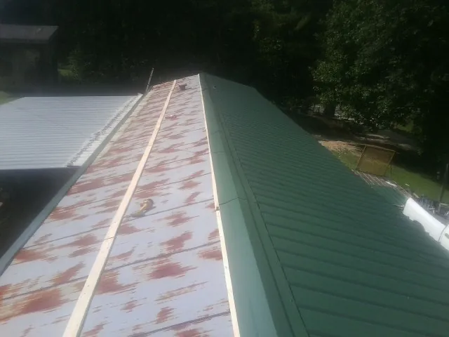 Old rusted panels beside newly installed green metal roofing — Wind Damage Roof Repair by Roofing Brothers in Brandeis
