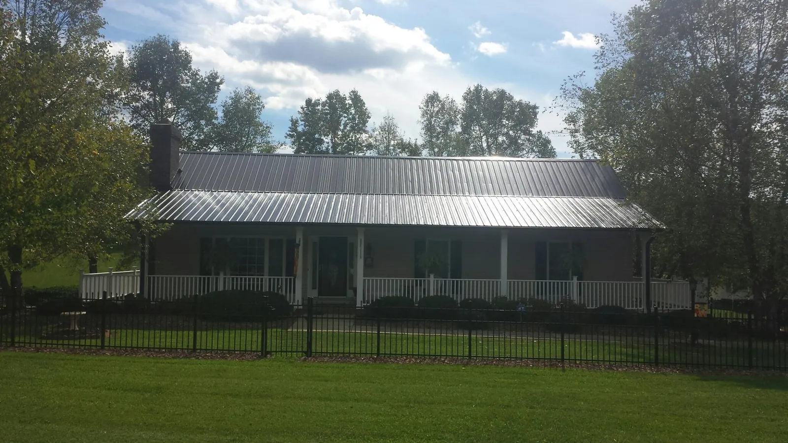 Gray metal roof on a brick ranch with a full width front porch — Gutter Guard Installation work by our crew in Brandeis
