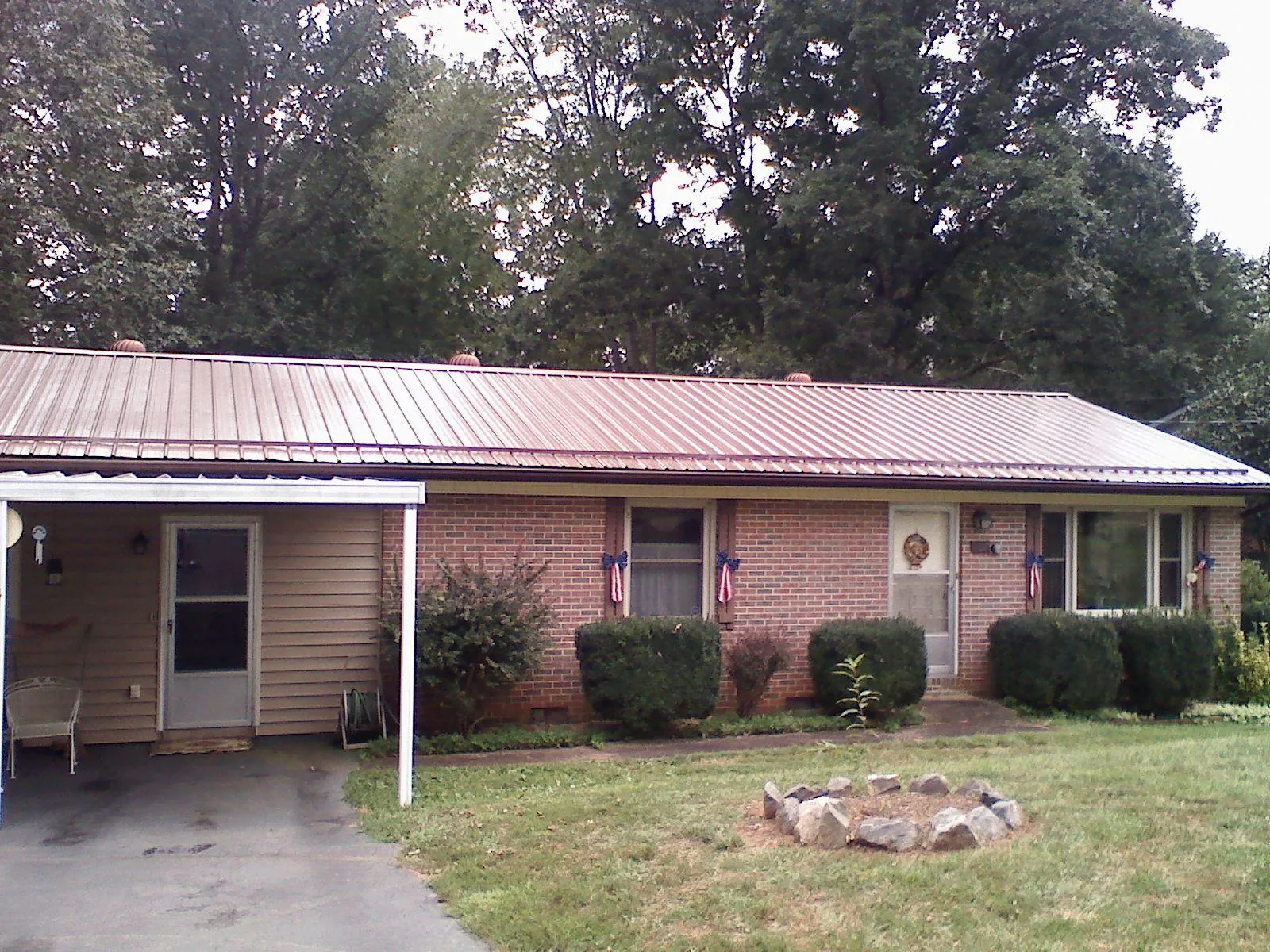 Bronze metal roof and carport on a brick ranch home — Roof Repair work by our crew in Brandeis